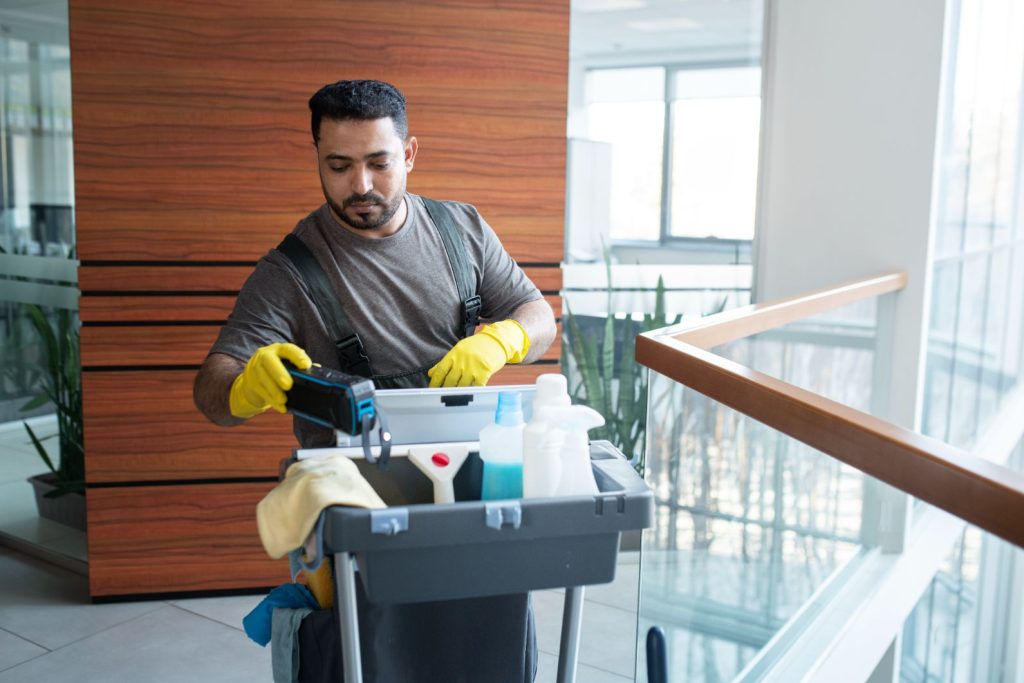 Medium shot man walking with cleaning cart for house cleaning service