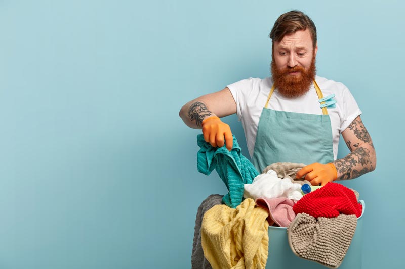 housekeeping-chores-concept-frustrated-redhead-bearded-man-holds-towel-chooses-dirty-stinch-laundry-from-basket